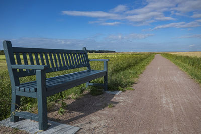 Empty road amidst field against sky