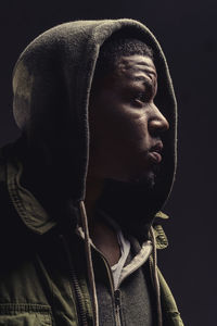 Close-up of thoughtful man wearing hooded short against black background