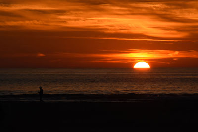 Silhouette man standing on beach at sunset