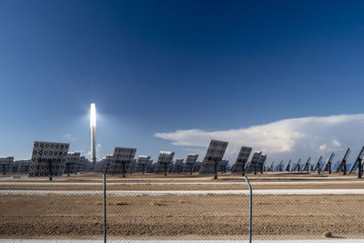 Illuminated street light amidst solar panels against sky