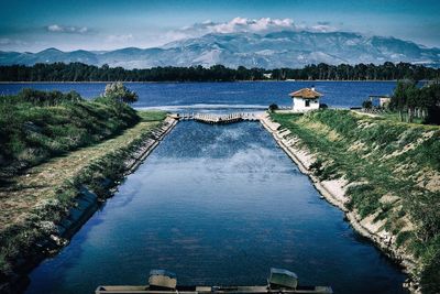 River with trees and mountains against cloudy sky