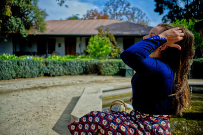 Woman with hand in hair sitting outdoors