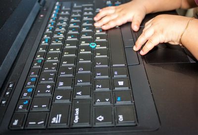 Cropped hands of child using computer