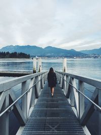 Rear view of woman walking on pier over sea