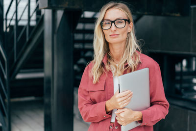 Elegant business woman stands and holds a laptop