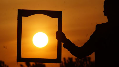 Close-up of hand holding camera during sunset