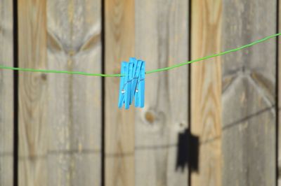 Close-up of clothes hanging on clothesline against blue fence