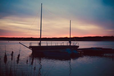 Silhouette boats in lake against sky during sunset