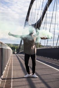 Rear view of man on footbridge against sky