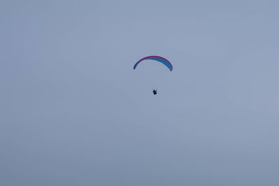 Low angle view of person paragliding against clear sky