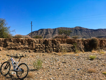 Bicycle on field by mountain against clear blue sky