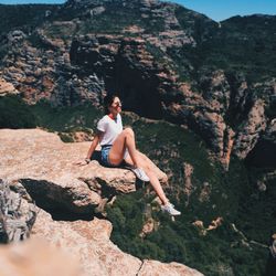 Young woman on cliff against mountains