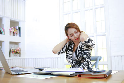 Young woman using phone while sitting on table