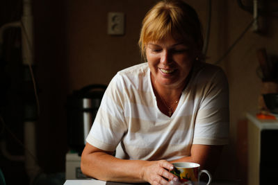 Happy young caucasian woman smiling while sitting at home with coffee or tea mug. morning routine in 