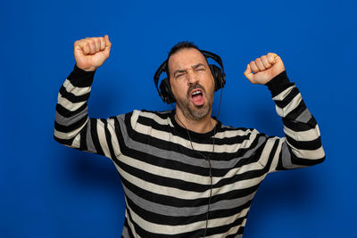 Portrait of man listening music against blue background