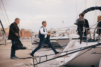 Senior women looking at men boarding yacht moored at harbor