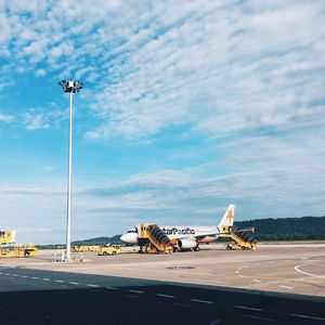 Airplane on airport runway against sky