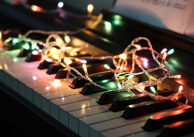Close-up of illuminated string lights over piano