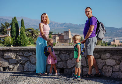 Rear view of family standing against wall