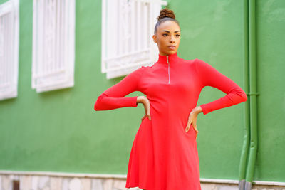 Portrait of young woman standing against building