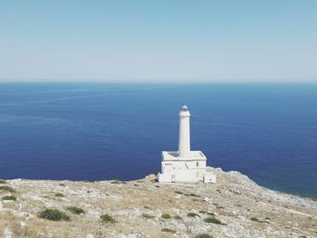 Lighthouse by sea against clear sky