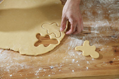 Cropped hands of chef cutting dough with pastry cutter at table