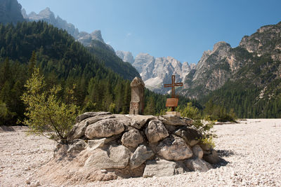 Rocks by trees on mountain against sky