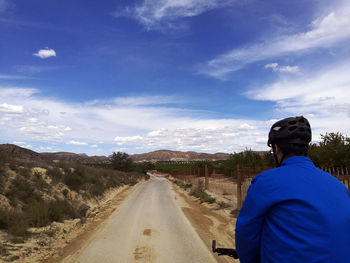 Rear view of man standing on road against sky