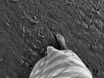 Low section of woman standing at sandy beach