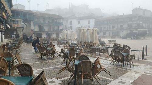 People on sidewalk cafe by buildings in city