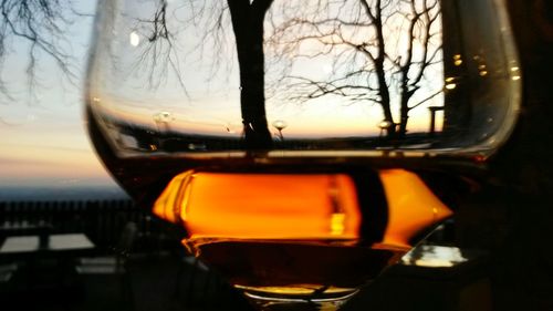 Close-up of beer glass against sunset sky