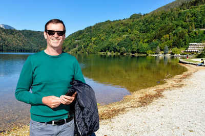 Portrait of smiling man standing by lake