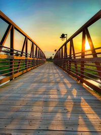 Footbridge over footpath against sky during sunset