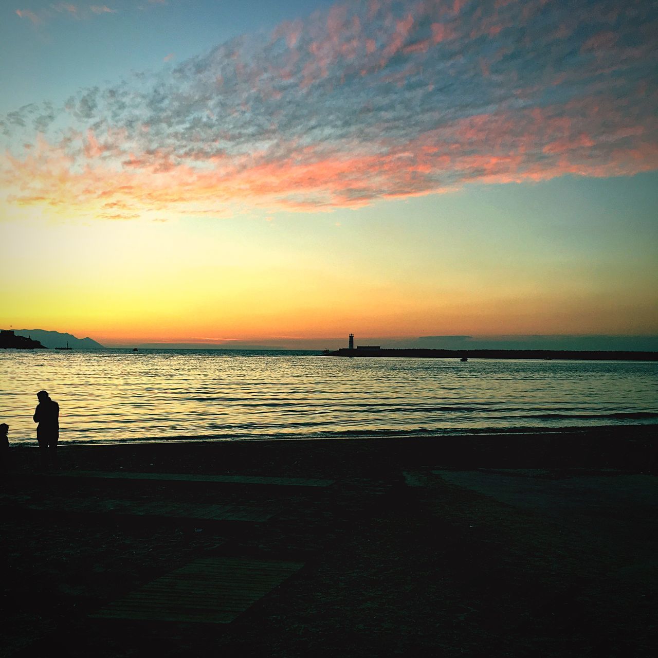 SILHOUETTE OF PERSON ON BEACH AGAINST SKY DURING SUNSET