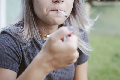 Close-up of woman igniting marijuana joint outdoors