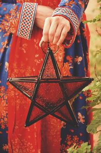 Midsection of woman holding star shaped lantern