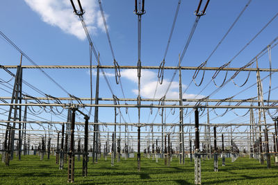 Low angle view of electricity pylon on field against sky