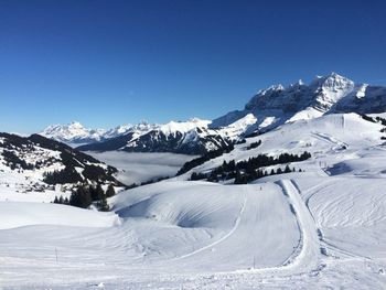 Scenic view of snowcapped mountains against clear blue sky