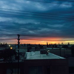 Illuminated city against sky at sunset