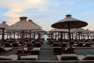 Chairs and tables on beach against sky