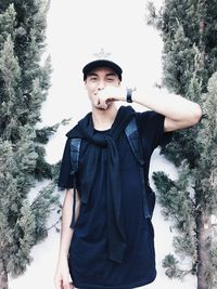 Portrait of young man standing against trees