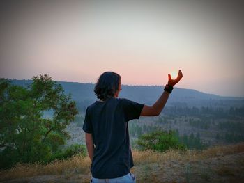 Optical illusion of man holding sun against sky during sunset