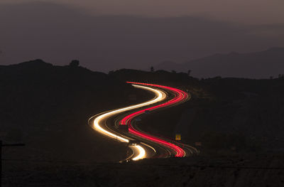 Light trails on highway against sky at night