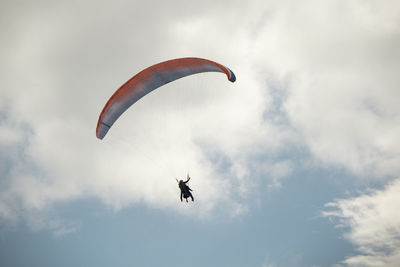 Low angle view of person paragliding against sky