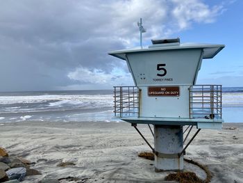 Information sign on beach against sky