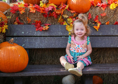 Smiling girl sitting on bench during halloween