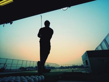 Rear view of silhouette man standing against sky during sunset