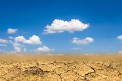 Surface level of barren landscape against blue sky