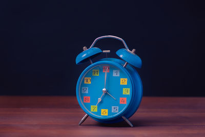 Close-up of clock on table against black background