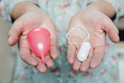 Midsection of woman holding tampon with menstrual cup